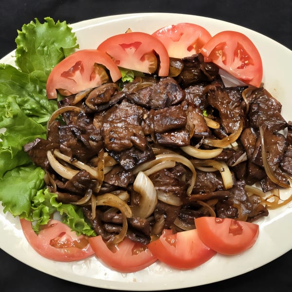 Vegan stir-fried beef with onions, lettuce, and tomato slices on a white plate.